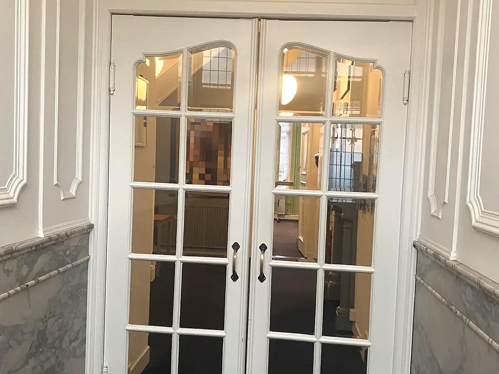 Stijlvolle entree met openslaande deuren en marmeren lambrisering